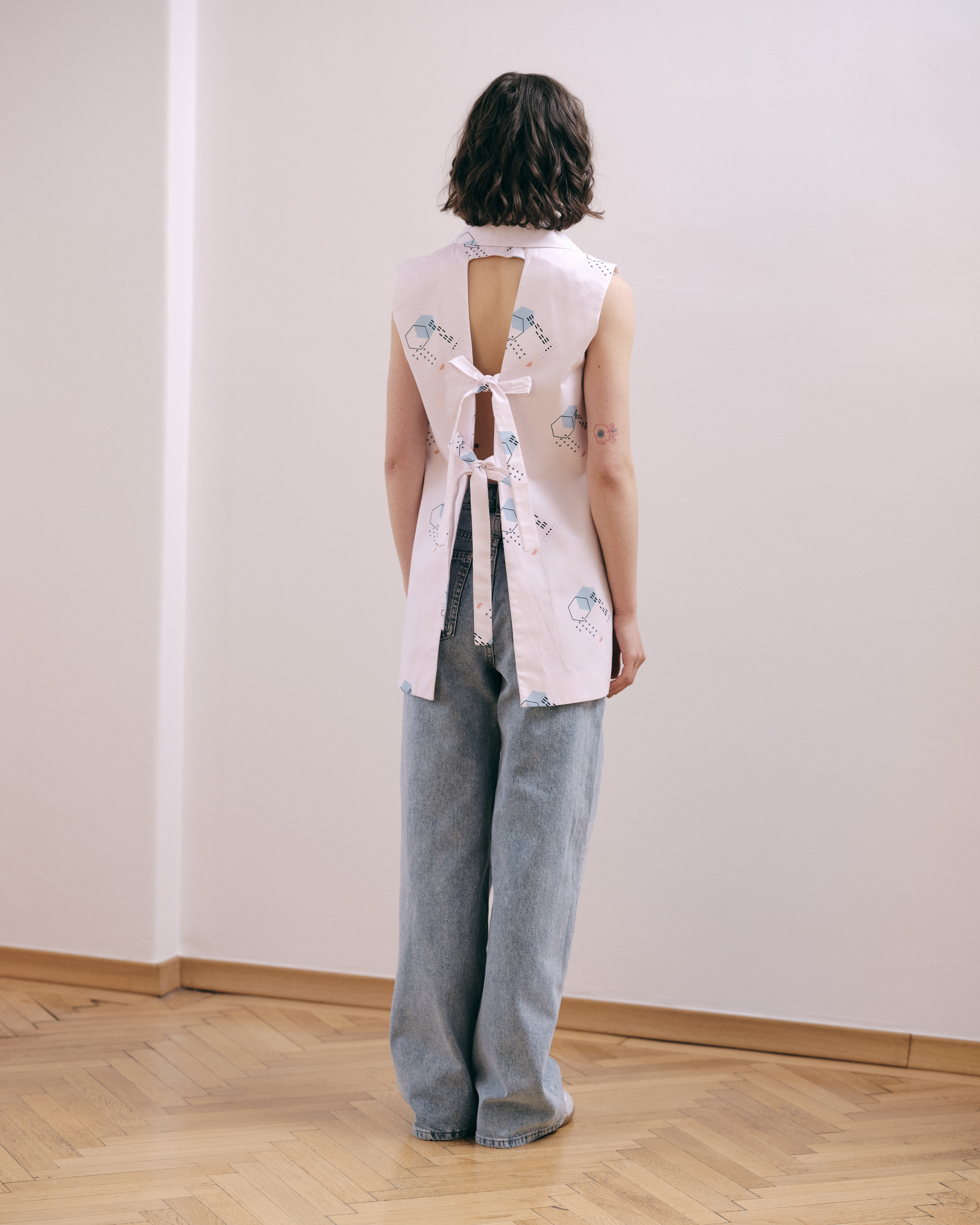 STRUCTURED, verb, construct or arrange according to a plan. Straight-cut oversize vest, with a geometric shawl collar. Unique patterns designed by the ROAD. The vest has an open back and ties that can be adjusted. Made in 100% cotton