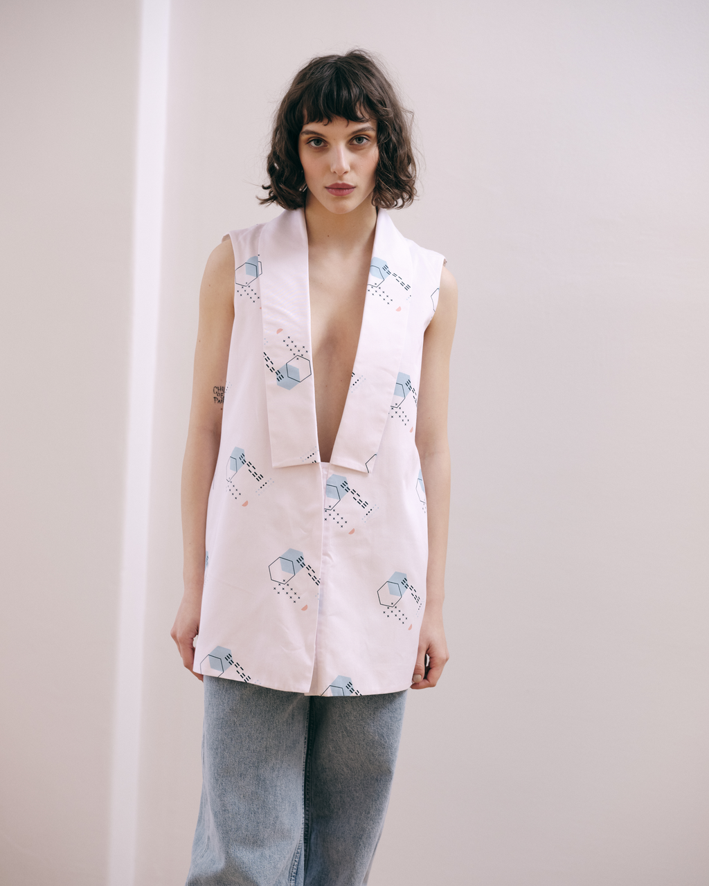 STRUCTURED, verb, construct or arrange according to a plan. Straight-cut oversize vest, with a geometric shawl collar. Unique patterns designed by the ROAD. The vest has an open back and ties that can be adjusted. Made in 100% cotton
