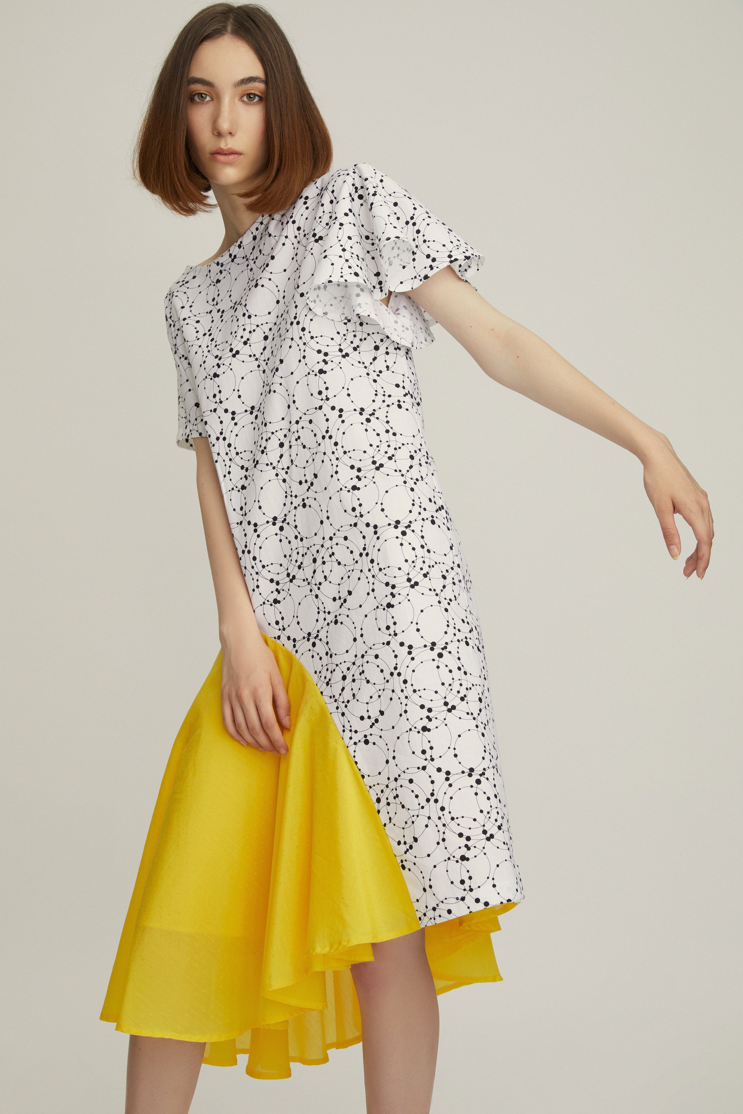 A modern construction, this dress has a back V-neck with a removable yellow dotted silk cord. The sleeves epitomize diversity, you will notice one angled sleeve and one draped. Made from pure cotton with a thick, tactile quality, it has a straight fit and falls just above the knee.