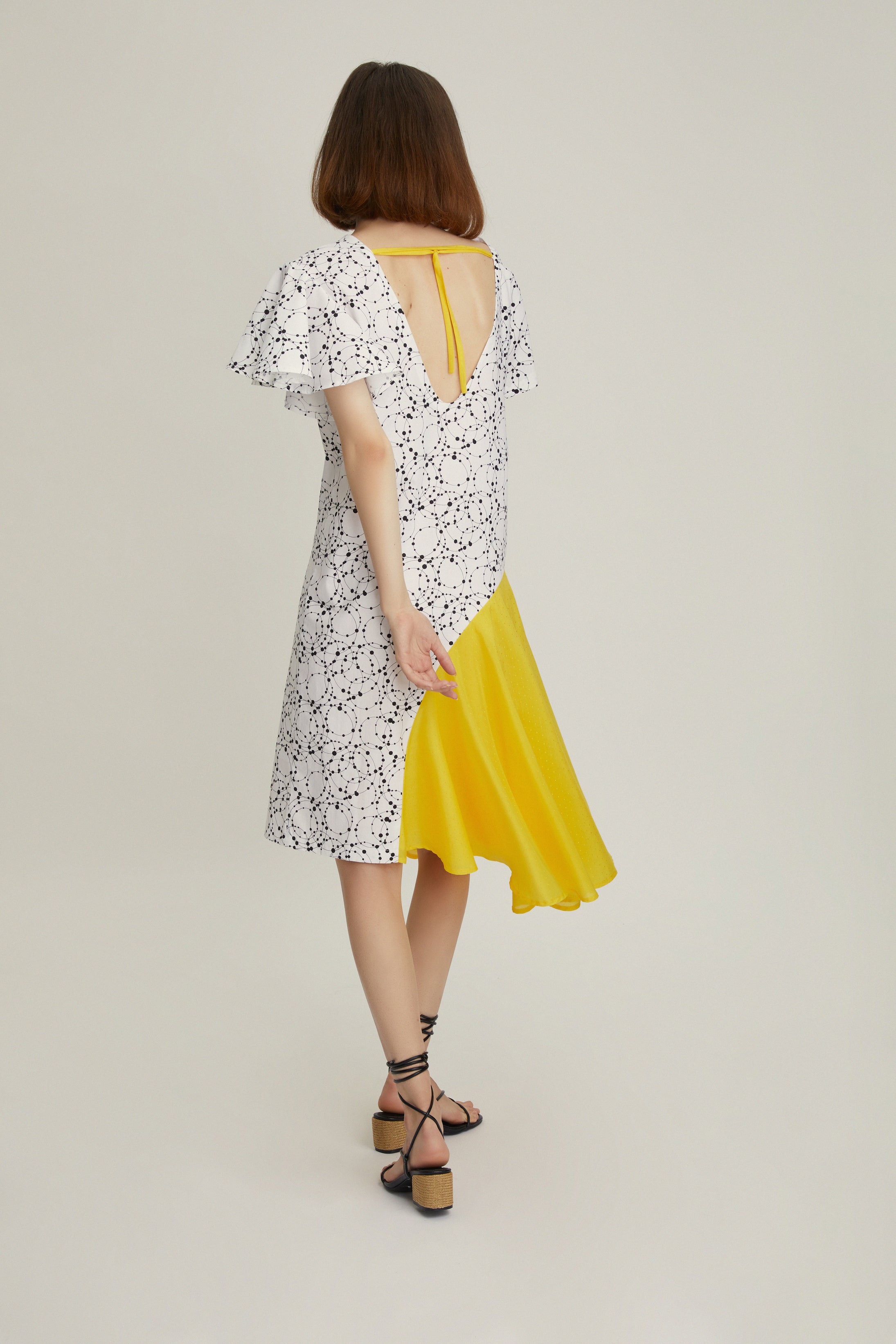 A modern construction, this dress has a back V-neck with a removable yellow dotted silk cord. The sleeves epitomize diversity, you will notice one angled sleeve and one draped. Made from pure cotton with a thick, tactile quality, it has a straight fit and falls just above the knee.